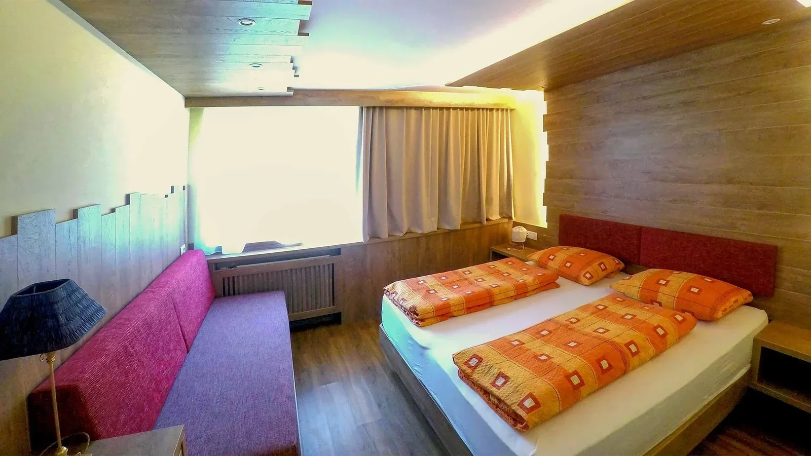 Doppelzimmer im Appartement Typ C Dolomiti mit Sofa und Holzmöbeln