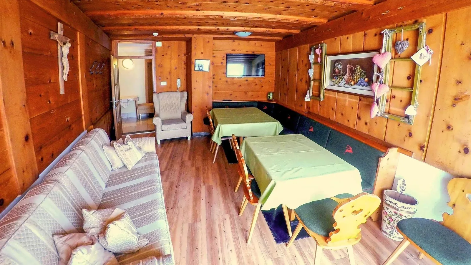 Tiroler Stube im Appartement Typ C Dolomiti mit zwei Tischen und umlaufender Sitzbank